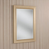 The Rimini Rectangle Wall Mirror - Gold, featuring its luxurious light wooden frame, is mounted on a wall decorated with vertical beige and light brown striped wallpaper. The mirror gracefully reflects a soft, neutral interior that exudes understated elegance.