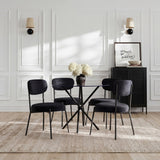 Smith dining chairs with black velvet seats and curved backrests on slim black metal legs, arranged around a round glass dining table in a panelled living room.