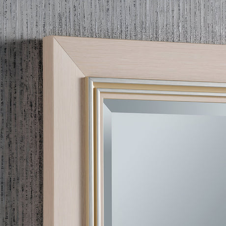 A close-up of the Alaris Rectangle Wall Mirror - White against a textured gray wall reveals its wooden frame with a light finish and subtle detailing along the inner edge, providing a chic contemporary touch to minimalist modern interiors.