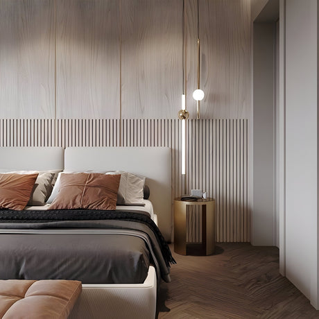 A modern bedroom features a beige upholstered bed with brown and gray bedding, accented by brown throw pillows. The Sottile LED Vertical Suspension Light in gold hangs beside a textured wood wall, elevating the minimalist design.
