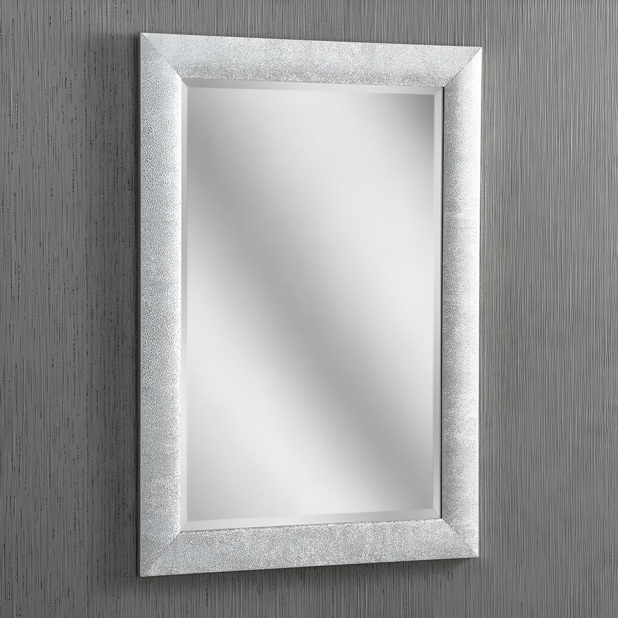 The Stardust Rectangle Wall Mirror - Silver, with its textured silver frame, adorns a vertically striped gray wall, exuding modern elegance. Its reflective surface displays no objects, creating a clean and minimalist aesthetic.