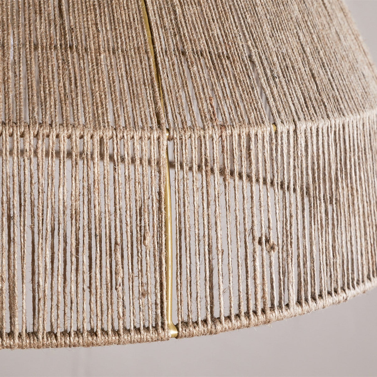 Close-up of the Tivi Natural Jute Lampshade, a dome-shaped shade with fine jute cord wound vertically over a visible brass frame, bound with a horizontal band near the rim.