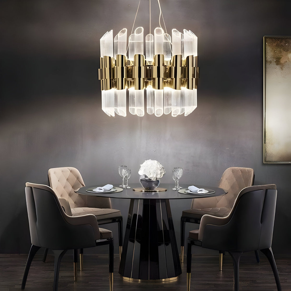 A modern dining room with a round black table for four, tufted beige and black chairs, and minimal dark wall decor. The Tycho 6 Light Crystal Chandelier in Gold & White hangs above, adding a touch of elegance with its ribbed glass elements.
