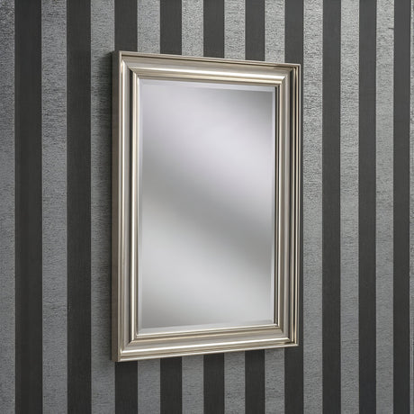 The Luxon Rectangle Wall Mirror - Silver is mounted on a wall featuring vertical black and gray stripes. Its blurred reflection captures a modern, minimalist aesthetic, making it ideal for contemporary home decor.