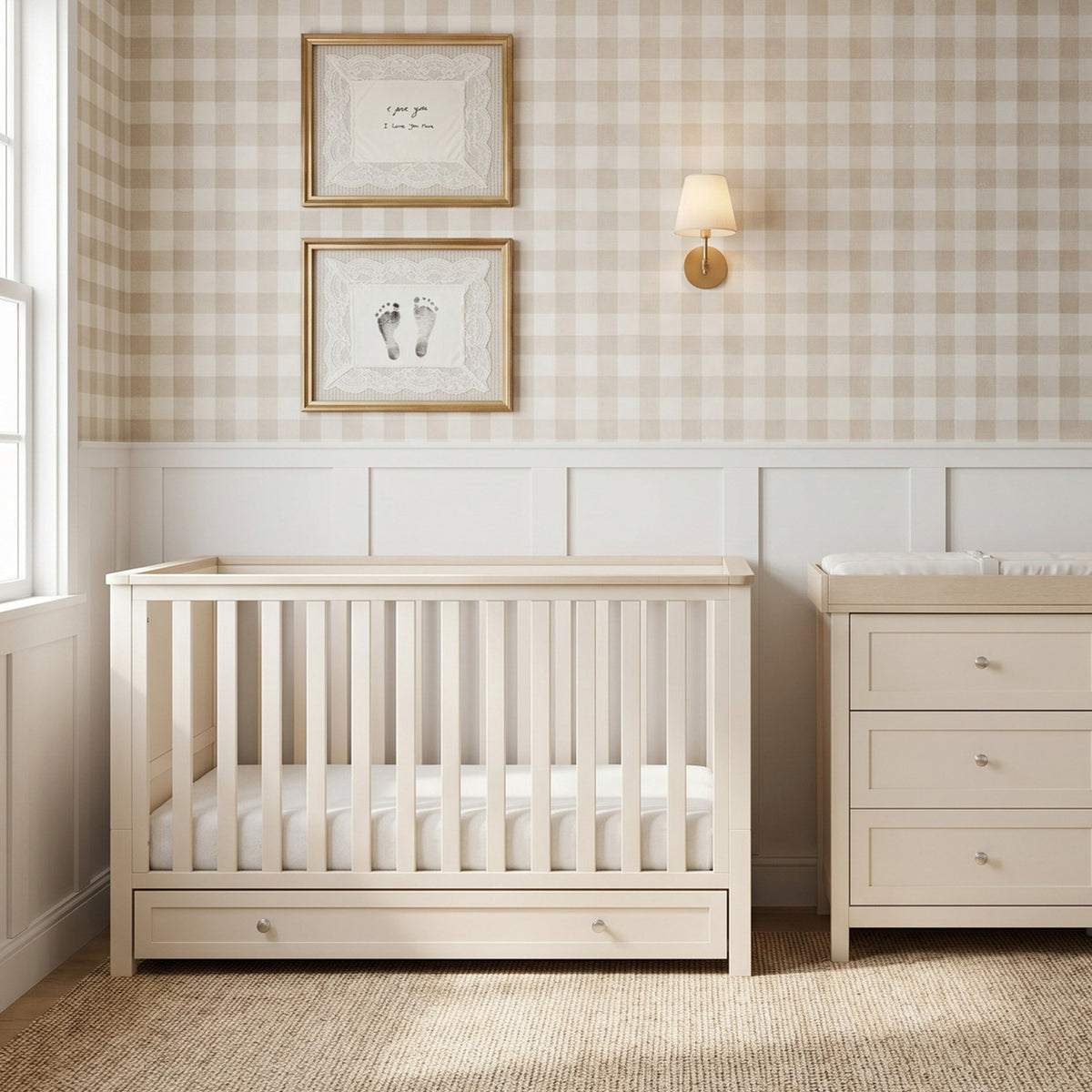 Wanderer Convertible Cot Bed with Drawer in Cashmere, cream slatted wood cot with under-bed storage drawer, shown in a nursery beside a matching dresser and gingham wallpaper.