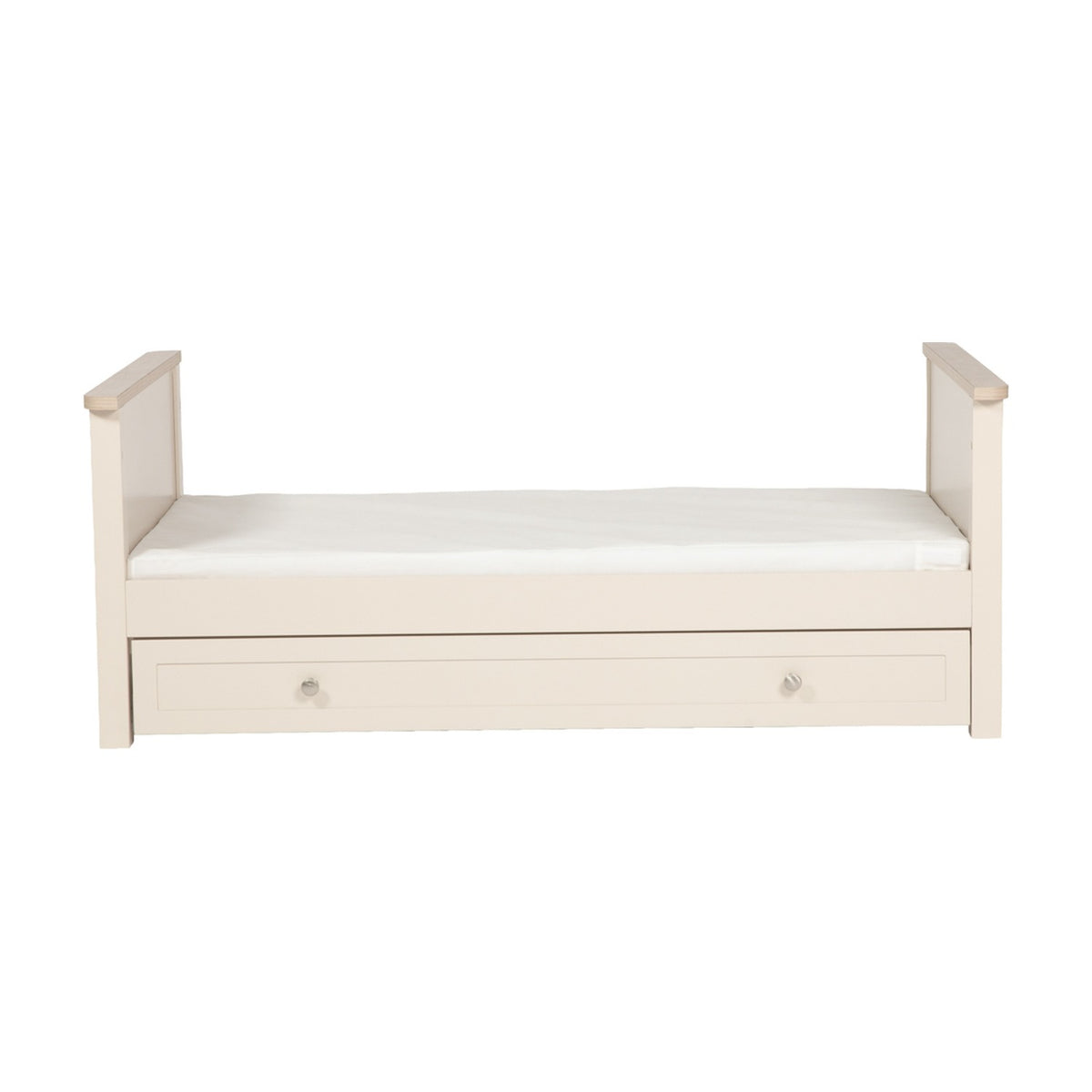 Wanderer Convertible Cot Bed with Drawer in Cashmere, cream toddler bed with raised end panels, oak-effect trim, white mattress, and a knobbed under-bed storage drawer on a plain white background.