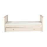 Wanderer Convertible Cot Bed with Drawer in Cashmere, cream toddler bed with raised end panels, oak-effect trim, white mattress, and a knobbed under-bed storage drawer on a plain white background.