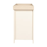 Wanderer Changing Table with Drawers & Removable Top in cashmere, side view showing tall tapered legs, oak-effect tray top, and flat cream panel side, on a plain white background.