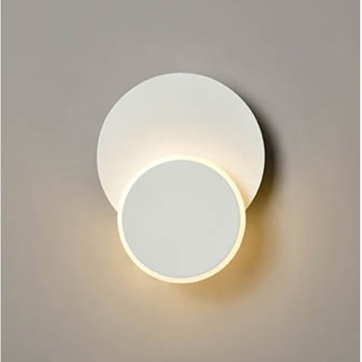 Crescent White Small LED Wall Light with two overlapping circular discs in matte white, the smaller disc glowing with warm light against a plain grey background.