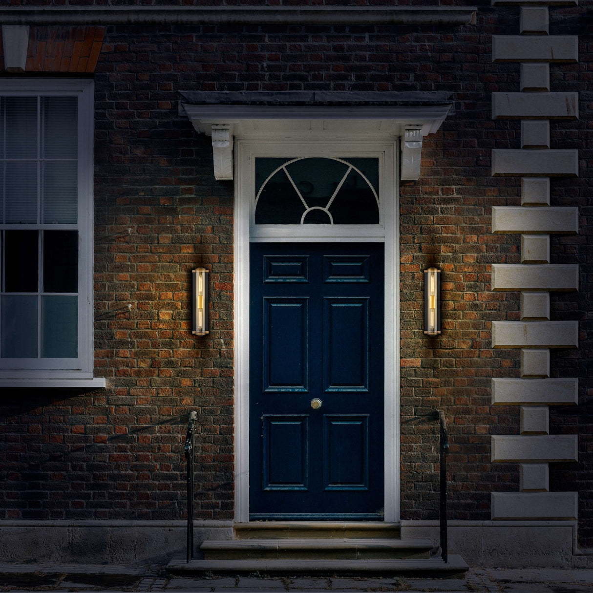 Charleston 2 light exterior wall light in black and brass finish, shown in a garden setting