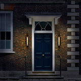 Charleston 2 light exterior wall light in black and brass finish, shown in a garden setting