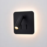 Luca Matt Black LED Wall Light with a square backplate, adjustable cylindrical reading spotlight, two toggle switches, and a soft ambient glow around the edges, shown on a plain white background.