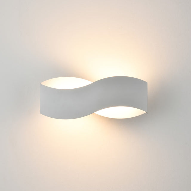 Infinity Matt White LED Wall Light with a curved metal S-shaped body, uplighting and downlighting softly against a plain white wall.