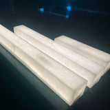 Valmera LED Slim Vertical Alabaster Wall Light in soft white, four rectangular alabaster columns shown lit from within, displayed on a dark reflective surface.