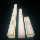Three vertical alabaster blocks in graduated heights, showing the Valmera LED wall light's natural stone texture in soft white against a dark background.