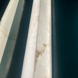 Close-up of the Valmera slim vertical wall light showing the natural veined alabaster column texture in soft white, mounted against a dark background.