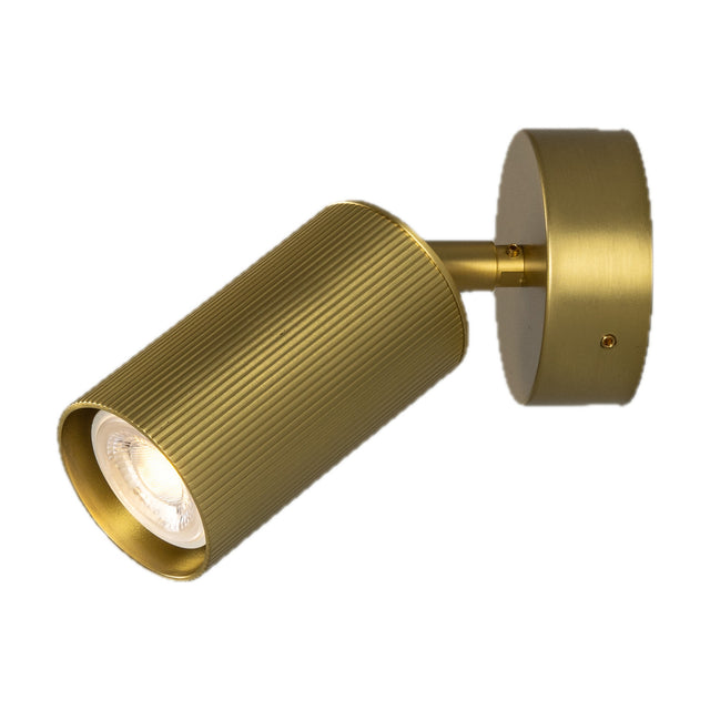 Adare Brass Wall Spotlight with a ribbed cylindrical head on a short arm, mounted to a round wall plate, shown lit against a plain white background.