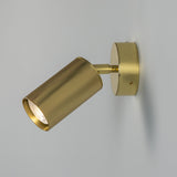 Adare Brass Wall Spotlight with a ribbed cylindrical head on a short arm, mounted to a round brass wall plate, shown against a plain light grey background.