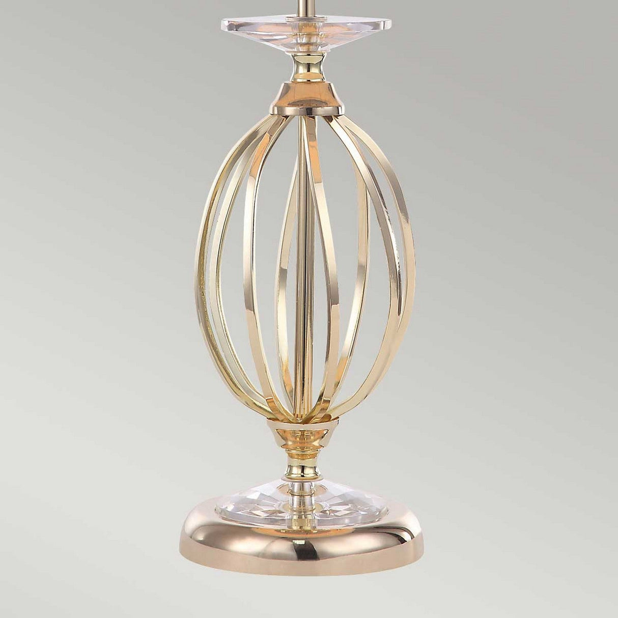 The Aegean Table Lamp - Polished Brass features an open, spherical gold-metal frame with a polished brass finish and a robust base. Its elegant design includes sleek, curved lines and a reflective surface, adding a touch of modern sophistication.