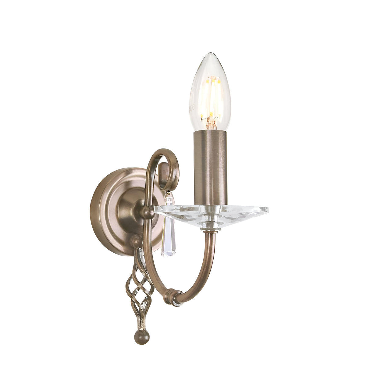 Introducing the Aegean Wall Light in Aged Brass, this vintage-style cut glass sconce features a single candle-shaped bulb perched on a gracefully curved arm, adorned with a decorative crystal accent. It's elegantly mounted on a round backplate that showcases an ornate design, making it ideal for any classic setting.