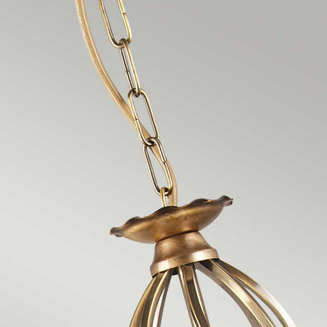 Close-up of the Aegean 3 Light Chandelier - Aged Brass chain and canopy, showcasing a decorative curved design. The image highlights the intricate metalwork details reminiscent of aged brass hand-forged scrolls, set against a neutral background.