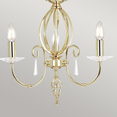 The Aegean 3 Light Chandelier - Polished Brass exudes luxurious lighting with its polished brass finish, curved arms, and candle-style bulbs. It features cut-glass droplets and a central ornate design that stands out beautifully against a neutral background, creating a stunning visual impact.