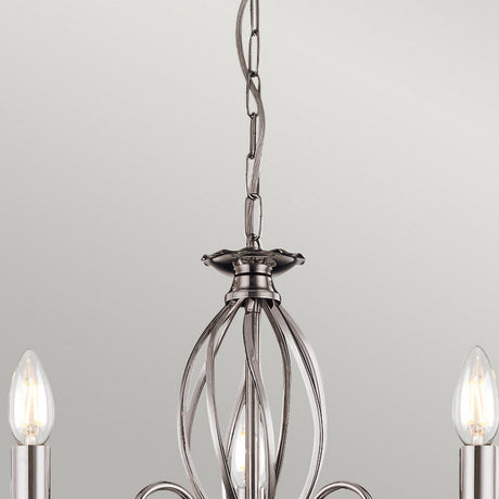 Close-up of the Aegean 3 Light Chandelier - Polished Nickel, showcasing three exposed bulbs. The fixture highlights an intricate open metalwork design with a hanging chain, set against a plain, light-colored wall.