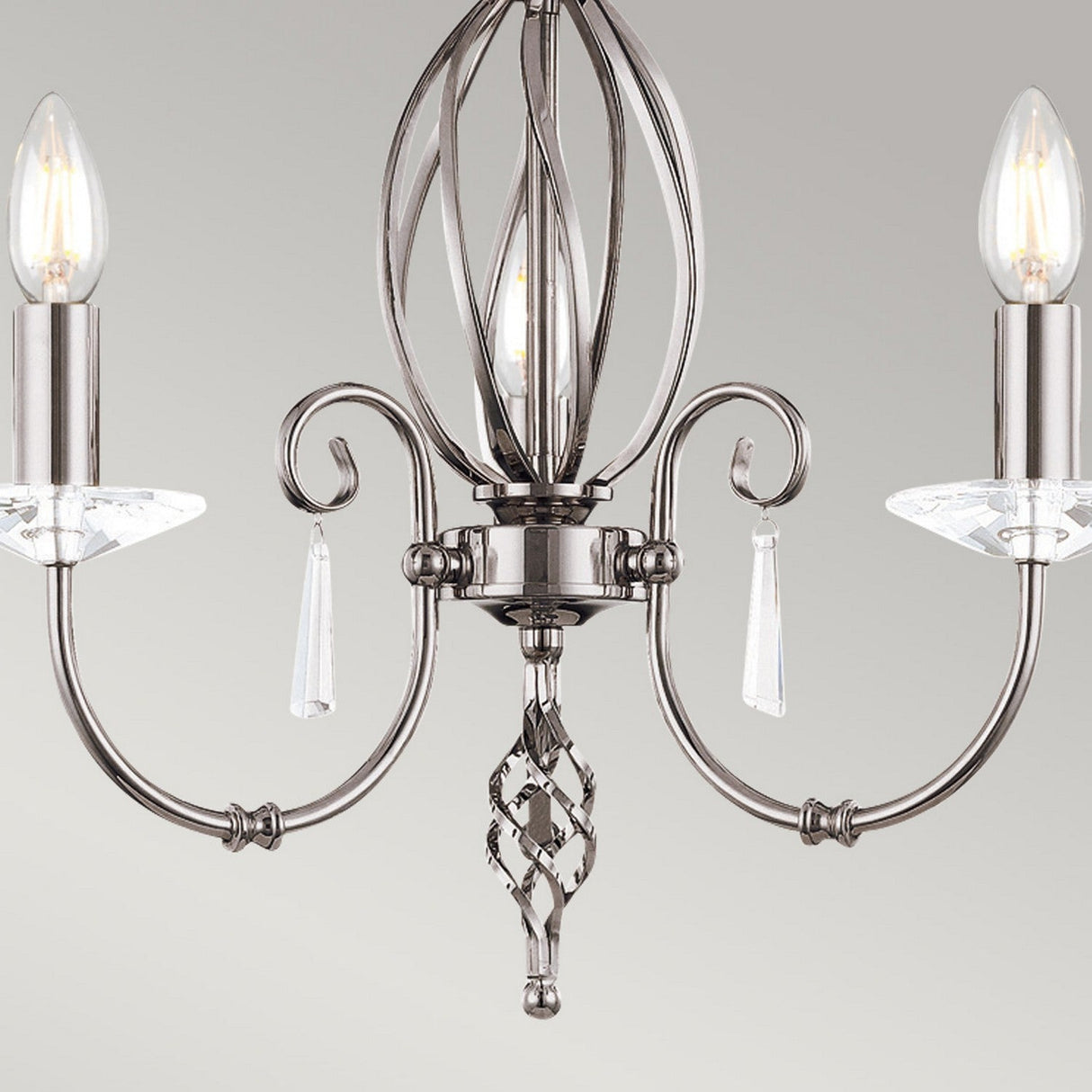 Presenting the Aegean 3 Light Chandelier - Polished Nickel, a contemporary lighting fixture showcasing a central ornate design and three gracefully curved arms, each holding candle-shaped bulbs adorned with crystal accents. Its elegant finish in polished nickel is beautifully complemented by a neutral light gray backdrop to enhance its timeless appeal.