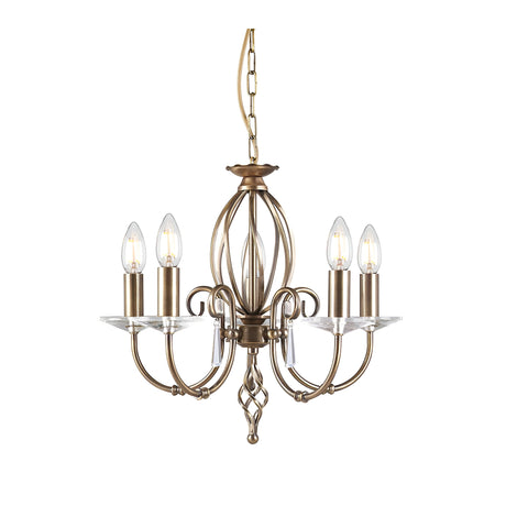 The Aegean 5 Light Chandelier - Aged Brass is a timeless piece featuring five candle-shaped bulbs. With elegantly hand-forged scrolls and an aged brass finish, it showcases curved arms and a central ornate column, all suspended by a matching chain.