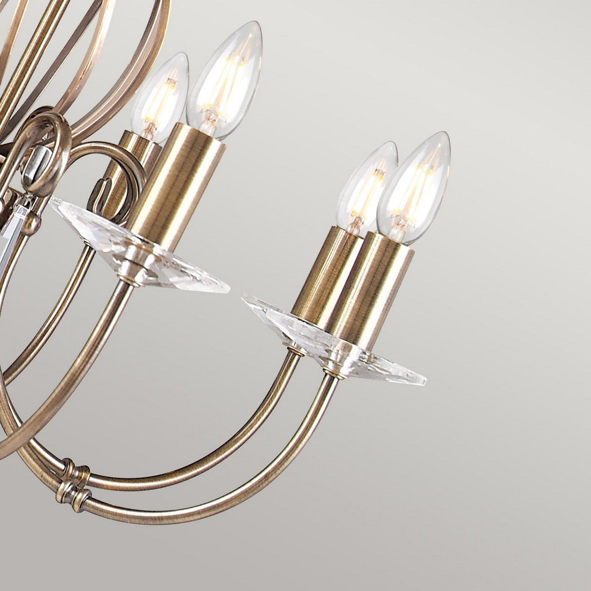 Close-up of the Aegean 8 Light Chandelier in aged brass, highlighting its vintage charm with multiple curving arms and candle-shaped light bulbs against a plain background.