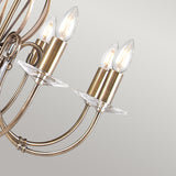 Close-up of the Aegean 8 Light Chandelier in aged brass, highlighting its vintage charm with multiple curving arms and candle-shaped light bulbs against a plain background.