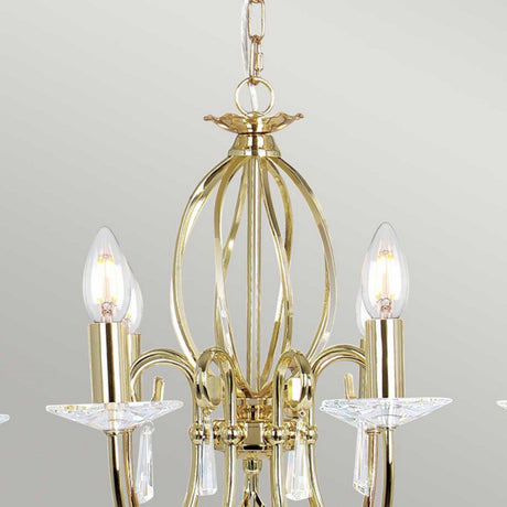 Introducing the Aegean 8 Light Chandelier - Polished Brass, a breathtaking piece with a modern gold design. It features eight candle-shaped light bulbs complemented by cut glass crystal accents. Suspended gracefully from a chain, it exudes elegance against a neutral backdrop with its polished brass finish.