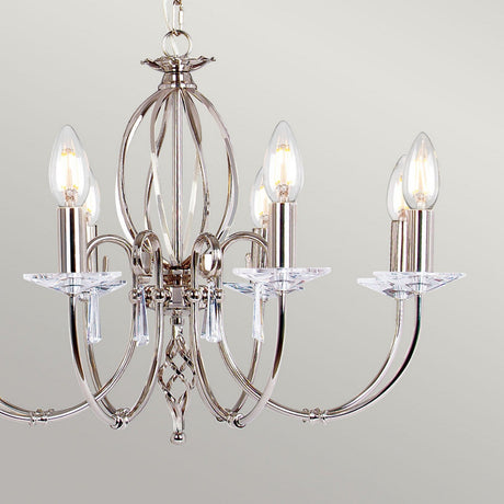 Displayed against a neutral background, the Aegean 8 Light Chandelier in polished nickel features a contemporary design with five candle-shaped light bulbs and decorative curved arms, enhanced by elegant clear accents.