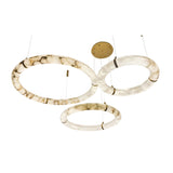 Niori Aureon LED triple ring pendant light with three alabaster hoops in varied sizes, suspended at staggered heights from a brushed brass round canopy.