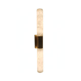 The Eryon LED Large Alabaster Wall Light features two frosted white cylinders, held by a central brushed brass bracket, creating a modern look in soft white against a plain background.
