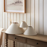 Endon Aldmere tapered lamp shades in natural faux linen, three sizes grouped on a wooden console table against cream panelled walls.
