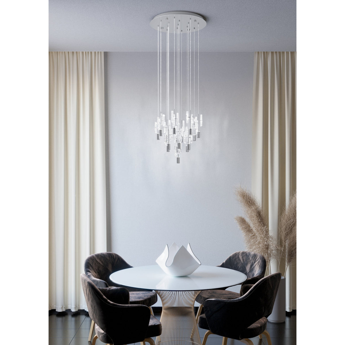Alemdina 15-light cascading pendant in chrome, with clear glass rods on a round chrome canopy, hung above a round dining table in a neutral-toned room.