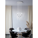 Alemdina 15-light cascading pendant in chrome, with clear glass rods on a round chrome canopy, hung above a round dining table in a neutral-toned room.