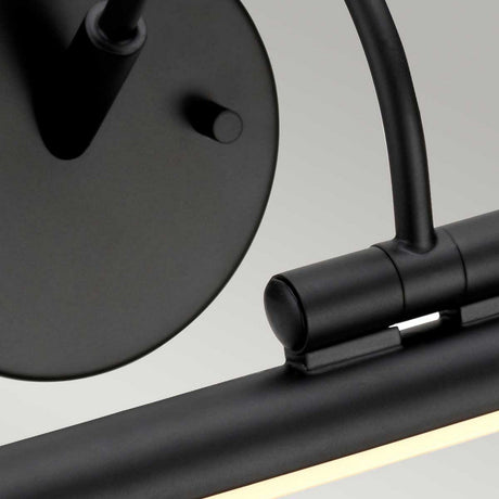 Product close-up of the Alton 1 Light Large LED Picture Light in black, showcasing its modern cylindrical design. It includes a round backplate and an adjustable arm extending to a horizontal LED light bar, all elegantly finished in black.