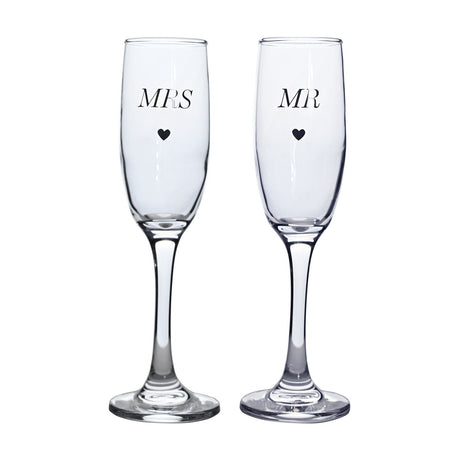 Set of 2 clear glass champagne flutes with tall narrow bowls and slim stems, printed with "MRS" and "MR" and small hearts, shown on a plain white background.