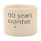 Round white ceramic double wick scented candle with "60 years together" printed in black lettering, shown on a plain white background.