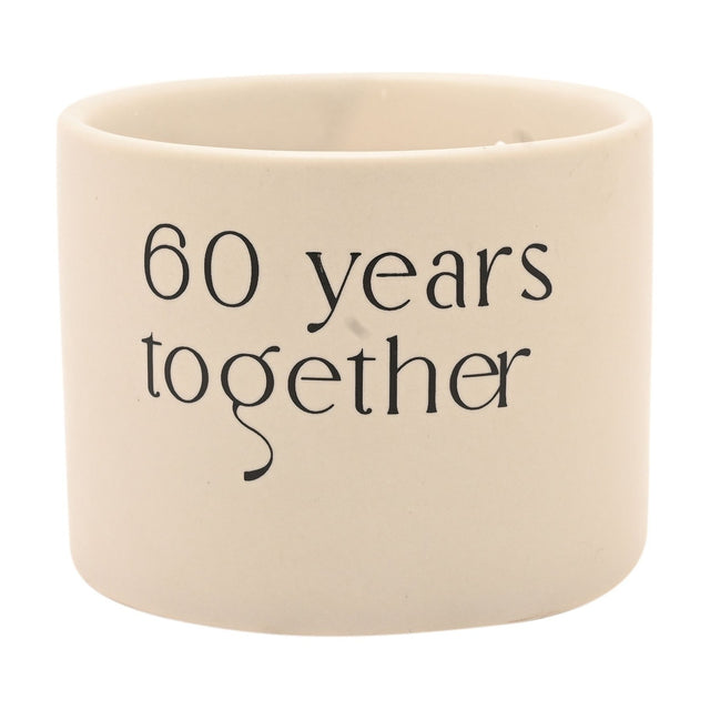 Round white ceramic double wick scented candle with "60 years together" printed in black lettering, shown on a plain white background.