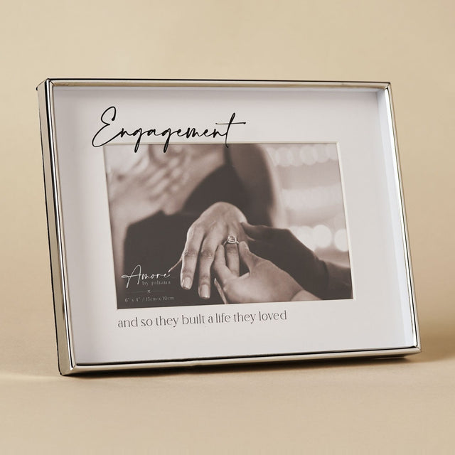 Silver rectangular glass photo frame with "Engagement" in script above a 6 x 4in photo and "and so they built a life they loved" beneath, set on a neutral background.