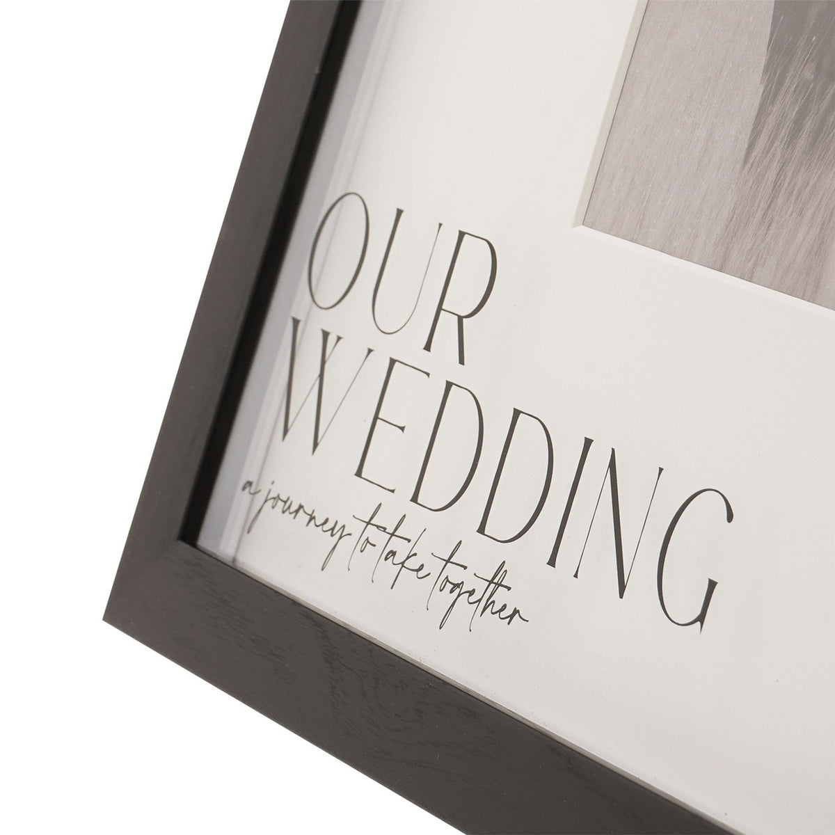 Close-up of the Our Wedding plastic easel photo frame, black woodgrain-effect edge with white mount reading "OUR WEDDING – a journey to take together" above a 6 x 4in photo window.