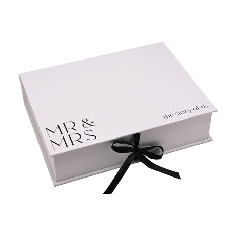 White linen A4 keepsake box with "MR & MRS" and "the story of us" in black text on the lid, closed with a black ribbon tie, shown on a plain white background.