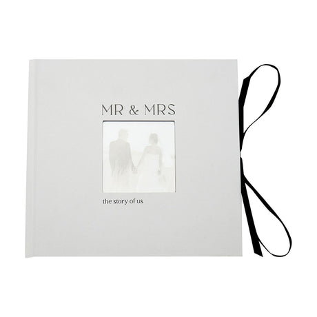 White textured wedding photo album with "MR & MRS" lettering, a small square photo window, "the story of us" text, and a black ribbon tie on the spine.