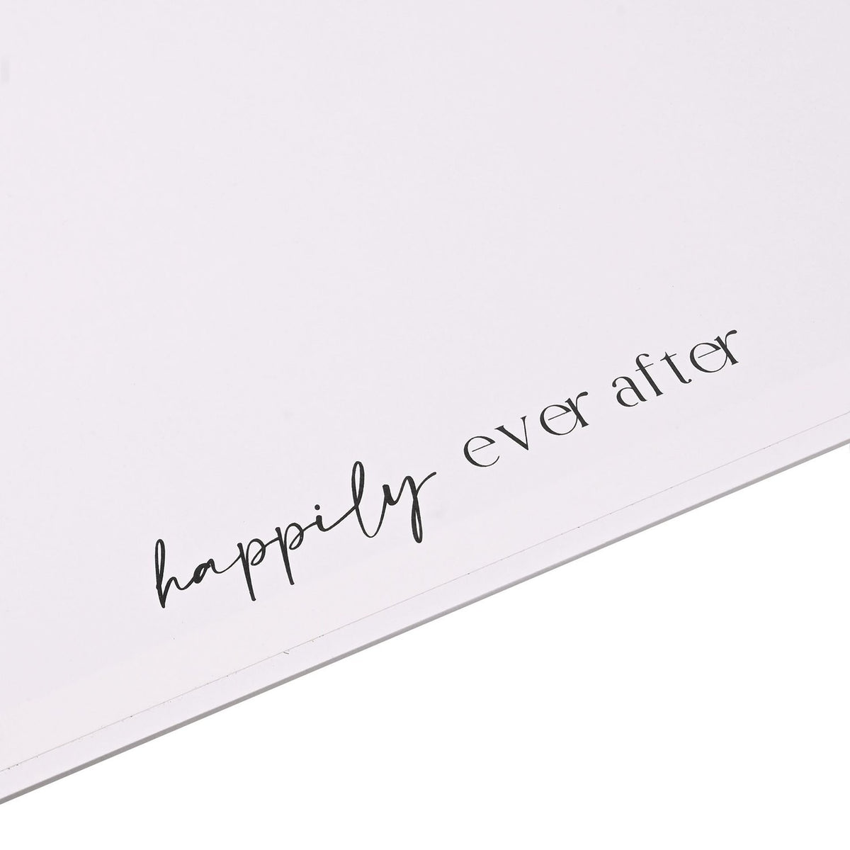 Close-up of the white square coffee table photo album's corner, showing "happily ever after" printed in black script across the cover.