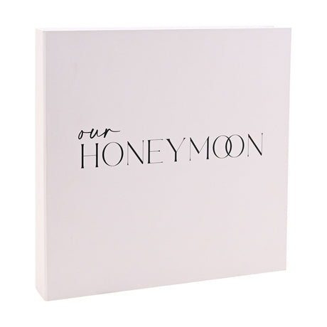 White square coffee table photo album with "our HONEYMOON" in black script and capital lettering, interlocking double-O design, on a plain white background.