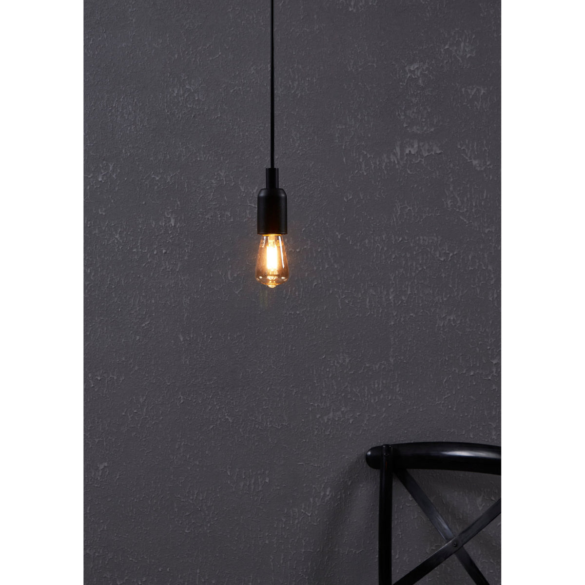 Amber LED bulb E27 with tapered glass body and visible filaments, lit warm white in a pendant fitting against a dark textured wall.
