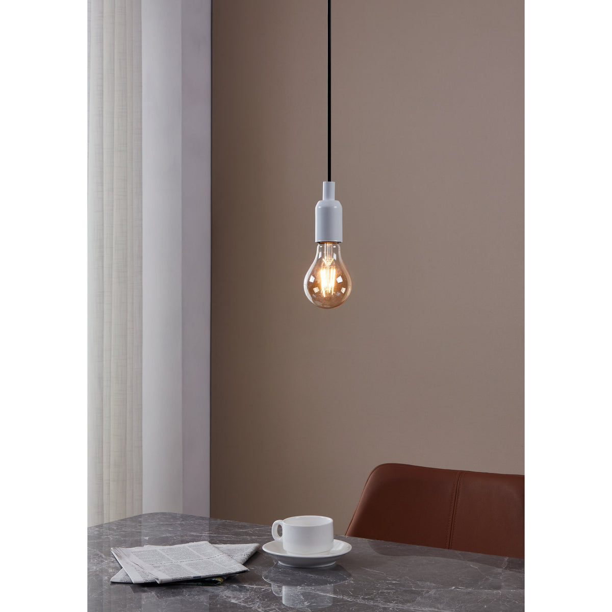 Amber LED Bulb E27, A-shaped glass bulb with visible filaments, shown lit in a white pendant fitting above a dining table in a warm-toned room.